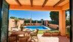 Covered terrace with direct pool access and surrounding garden area