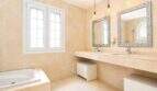 Luxuriöses Badezimmer mit Doppelwaschtisch, Badewanne und großzügiger Fensterfront