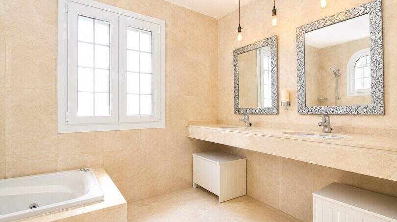 Luxuriöses Badezimmer mit Doppelwaschtisch, Badewanne und großzügiger Fensterfront