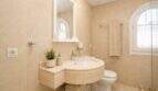 Edles Badezimmer mit Marmor-Wandverkleidung und begehbarer Dusche mit Glastür