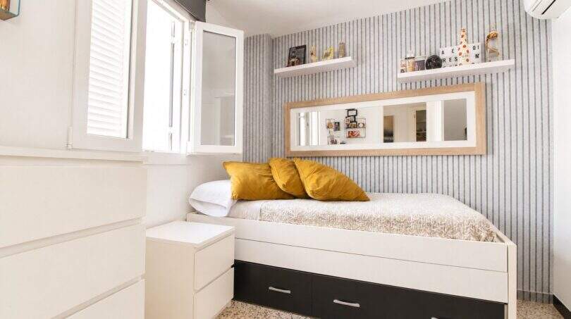 Helles Schlafzimmer mit Einzelbett, Stauraum, Spiegel und Streifentapete in Palma de Mallorca