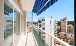 Sunny balcony with blue sun sail and city view of Palma de Mallorca, bright glass front