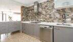 Moderne Küche mit Steinwand-Backsplash, grauen Schränken, Induktionskochfeld und Edelstahl-Dunstabzug in Palma-Stadtwohnung