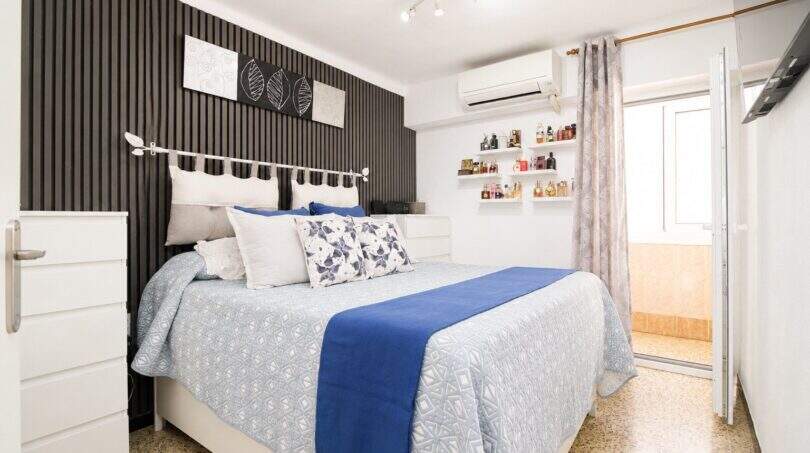Helles Schlafzimmer mit Doppelbett, blauer Bettwäsche, Klimaanlage und dekorativem Akzentpaneel in Palma
