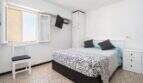 Helles Schlafzimmer mit Doppelbett, Wandklimagerät, TV und Fenster mit Jalousien in Palma de Mallorca