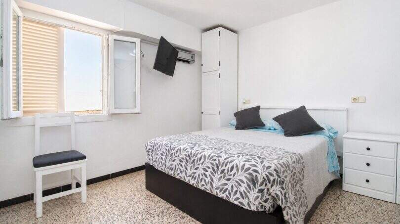 Helles Schlafzimmer mit Doppelbett, Wandklimagerät, TV und Fenster mit Jalousien in Palma de Mallorca