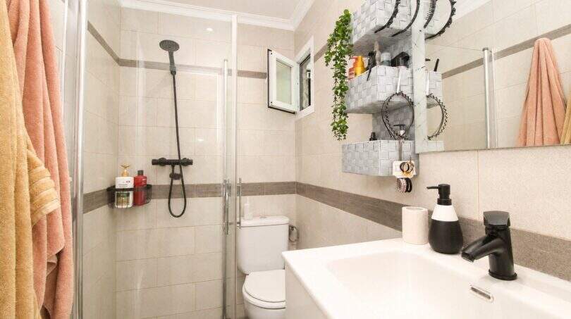 Modernes Badezimmer mit Glasdusche, schwarzen Armaturen und Wandregalen in Palma-de-Mallorca-Wohnung