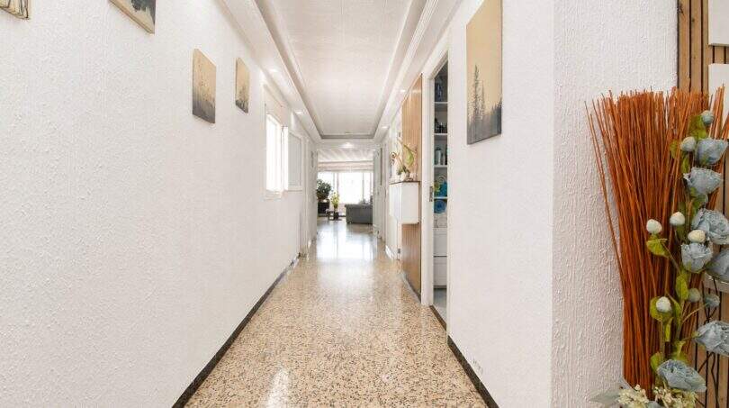 Langer heller Flur mit Terrazzoböden, weißen Wänden und Wandbildern in Stadtwohnung Palma de Mallorca