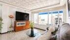 Helles Wohnzimmer mit Sofa, Flachbild-TV, Glastisch und großen Fenstern mit Stadtblick in Palma