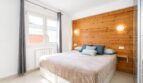 Helles Schlafzimmer mit Holzakzentwand und großzügigen Fensterflächenlichtern