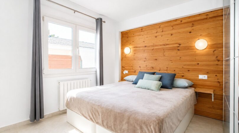 Helles Schlafzimmer mit Holzakzentwand und großzügigen Fensterflächenlichtern