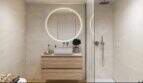 Modern bathroom with round mirror, wooden vanity and walk-in shower in the new Palma de Mallorca building