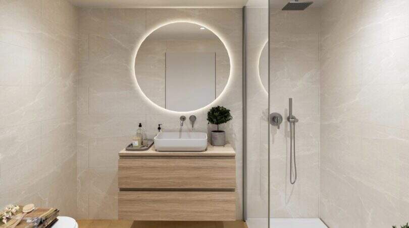 Modern bathroom with round mirror, wooden vanity and walk-in shower in the new Palma de Mallorca building