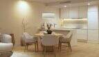 Bright living-dining room with wooden table, modern kitchen and warm design in new building Palma de Mallorca