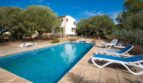 Villa Marratxí: Rechteckiger Pool mit Liegestühlen, weißes Ferienhaus, mediterrane Bäume, blauer Himmel.