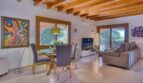 Lichtdurchflutetes Wohn-Esszimmer der Villa in Marratxí mit Holzbalkendecke, Glastisch und modernem TV-Bereich.