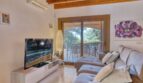 Helles Wohnzimmer der Villa in Marratxí mit Sofa, TV, Holzbalkendecke und Zugang zur Terrasse mit Gartenblick.