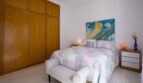 Helles Schlafzimmer der Villa in Marratxí mit Doppelbett, Holzeinbauschrank und buntem Wandgemälde.