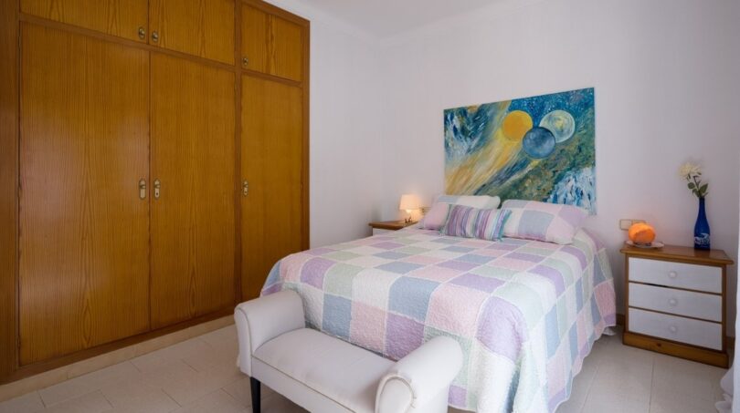 Helles Schlafzimmer der Villa in Marratxí mit Doppelbett, Holzeinbauschrank und buntem Wandgemälde.