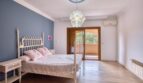 Helles Schlafzimmer der Villa in Marratxí mit Holzboden, blauer Akzentwand und Balkonzugang