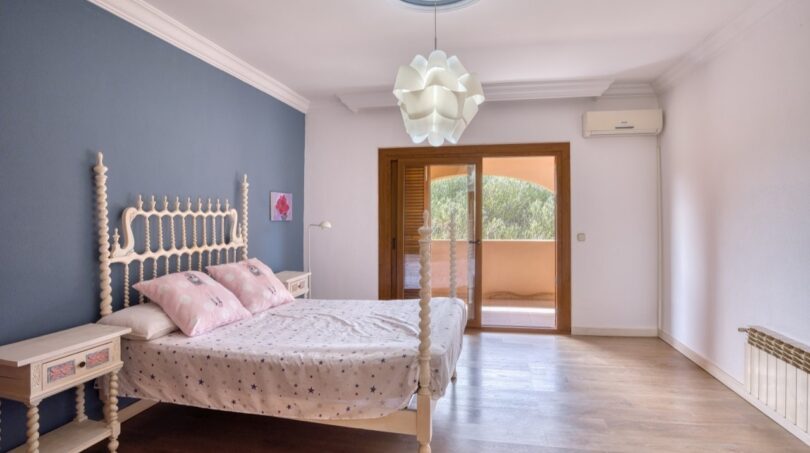 Helles Schlafzimmer der Villa in Marratxí mit Holzboden, blauer Akzentwand und Balkonzugang