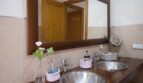 Badezimmer der Villa in Marratxí mit Doppelwaschbecken aus Edelstahl, Holzablage und großem Wandspiegel.