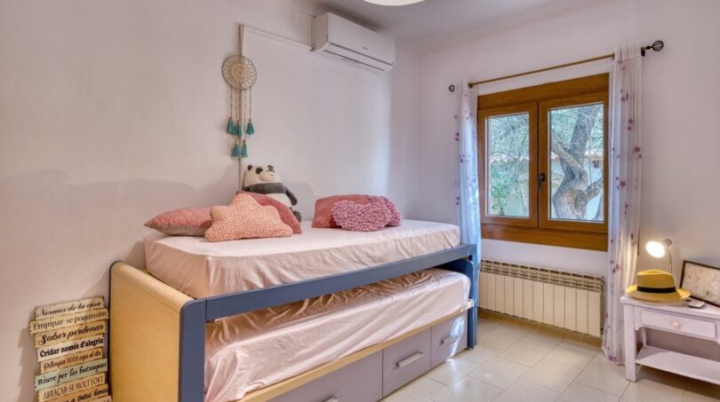 Kinderzimmer der Villa in Marratxí mit Etagenbett, Klimaanlage, Heizkörper und Fenster mit Gartenblick.