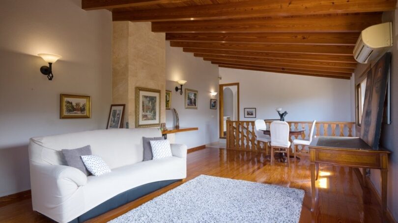 Helles Wohnzimmer der Villa in Marratxí mit Holzbalkendecke, weißem Sofa und angrenzendem Essbereich