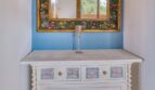 Vintage-Kommode mit Blumendekor und verziertem Goldspiegel in blauer Wandnische der Villa Marratxí