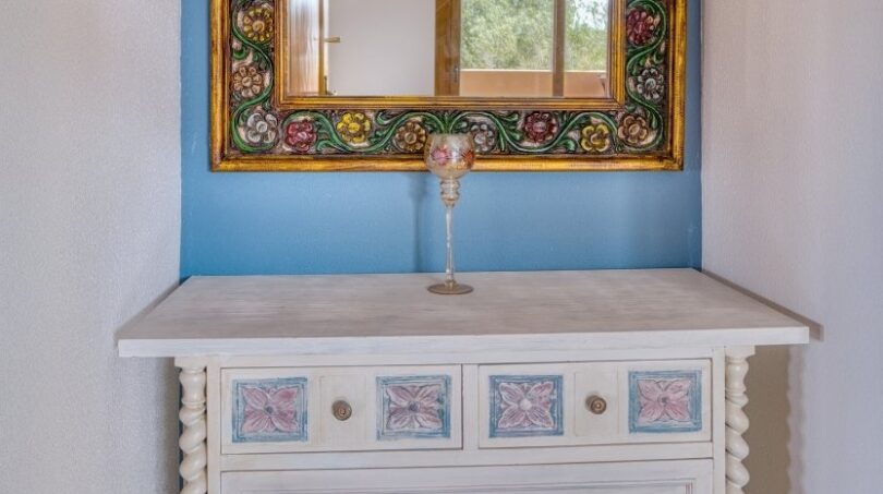 Vintage-Kommode mit Blumendekor und verziertem Goldspiegel in blauer Wandnische der Villa Marratxí