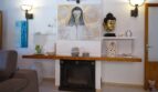 Wohnzimmer der Villa in Marratxí mit Kamin, Holzregal, Buddha-Skulptur und dekorativer Wandmalerei.
