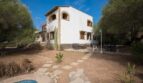 Außenansicht der Villa in Marratxí mit Pool, Steinweg, Terrasse und mediterranem Baumbestand unter blauem Himmel.