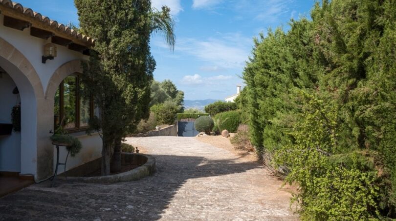 Gepflasterter Einfahrtsweg einer Villa in Marratxí mit mediterranen Zypressen und Blick auf die Landschaft.