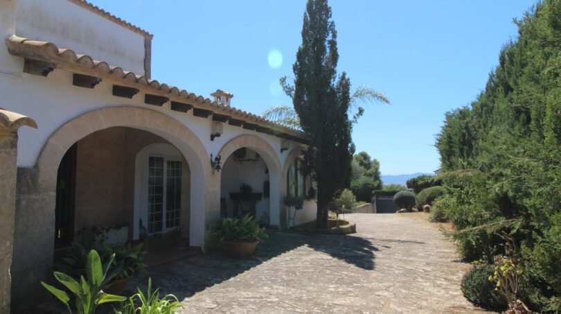 Eingangsbereich einer mediterranen Villa in Marratxí mit Rundbögen, Steinpflaster und üppigem Grün