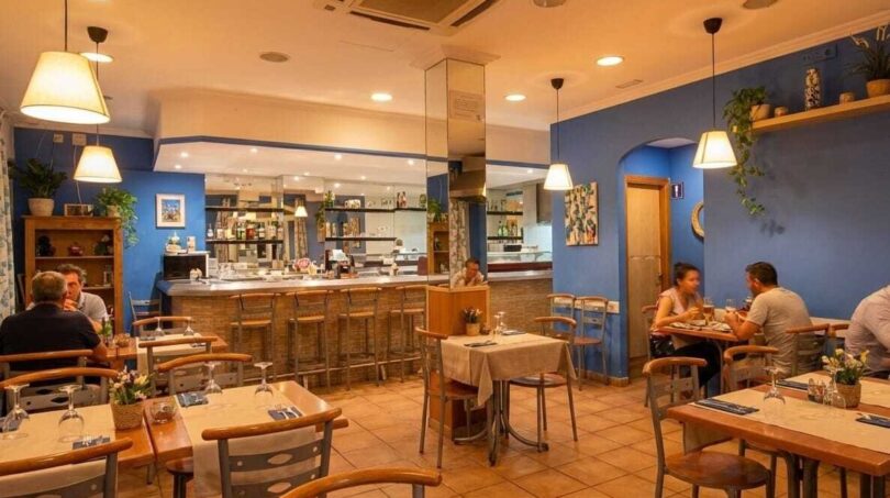 Restaurante mediterráneo con paredes azules, lámparas colgantes, bar e iluminación acogedora en Palma de Mallorca.