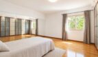 Dormitorio luminoso de la villa en Llucmajor con suelo de parquet, espejo empotrado y gran ventana con vista al jardín