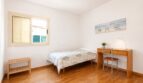 Dormitorio luminoso de la villa Llucmajor con cama individual, escritorio y suelo de parquet