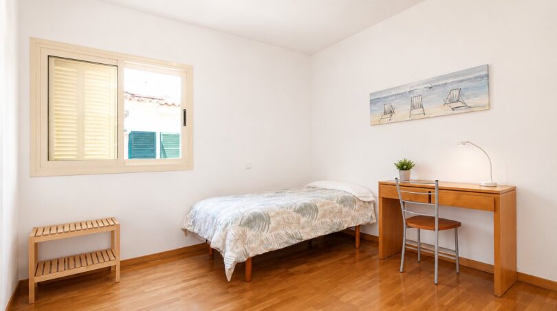 Dormitorio luminoso de la villa Llucmajor con cama individual, escritorio y suelo de parquet