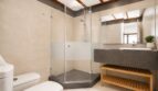 Cuarto de baño moderno de la villa en Llucmajor con ducha de cristal, lavabo gris y detalles de madera.