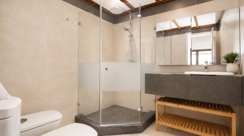 Cuarto de baño moderno de la villa en Llucmajor con ducha de cristal, lavabo gris y detalles de madera.