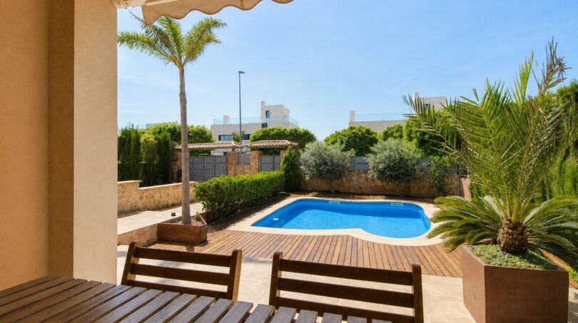 Terraza cubierta con muebles de madera y piscina privada, rodeada de palmeras y zonas verdes, villa Llucmajor
