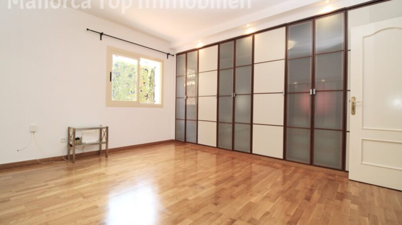 Dormitorio luminoso de la villa en Llucmajor con parquet de roble y elegante armario empotrado con puertas correderas de cristal