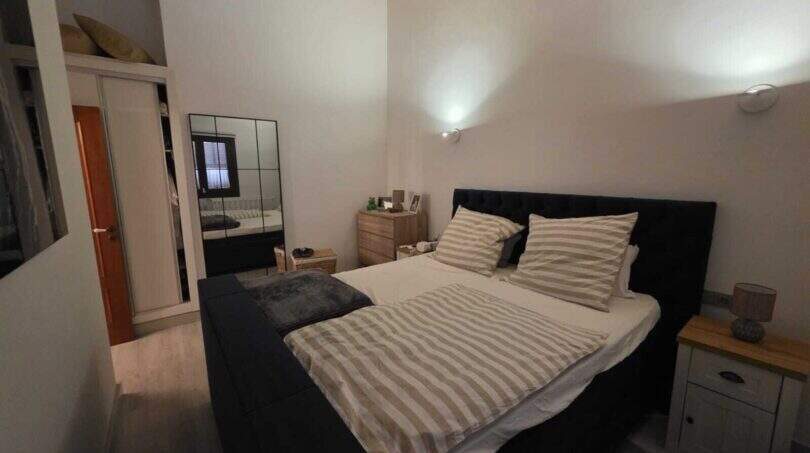 Schlafzimmer der Finca S'Illot mit Doppelbett, Holzbalkendecke und Spiegelschrank