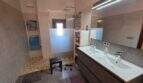 Modernes Badezimmer der Finca S'Illot mit Doppelwaschbecken, begehbarer Dusche und Naturstein-Boden.