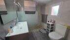 Modernes Badezimmer der Finca S'Illot mit Walk-in-Dusche, Waschtisch, WC und Fenster in Grautönen.