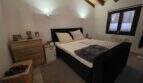 Schlafzimmer der Finca S'Illot mit Doppelbett, Holzbalkendecke und natürlichem Lichteinfall