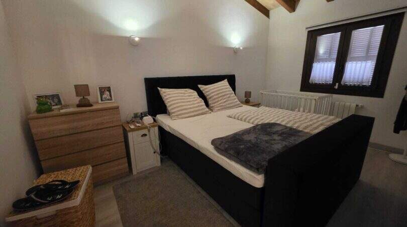 Schlafzimmer der Finca S'Illot mit Doppelbett, Holzbalkendecke und natürlichem Lichteinfall