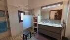 Modernes Badezimmer der Finca S'Illot mit Doppelwaschbecken, begehbarer Dusche und Holzbalkendecke.