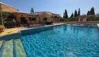 Finca S'Illot: Großer blauer Pool mit Sonnenterrasse, Pergola und mediterranem Garten im Hintergrund.