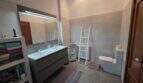 Modernes Badezimmer der Finca S'Illot mit Doppelwaschbecken, beleuchtetem Spiegel und WC
